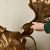 Close-up of a gold moose sculpture with a person’s hand touching its antler, highlighting the quirky, statement decor available at Urban Goods & Garden in Wilmington, NC.
