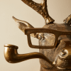 Close-up of a bronze deer sculpture wearing glasses and holding a pipe, showcasing the detailed and whimsical decor available at Urban Goods & Garden in Wilmington, NC.