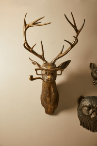 Bronze deer wall sculpture wearing glasses and a pipe, with additional quirky animal decor, reflecting Urban Goods & Garden’s playful and bold interior design flair in Wilmington, NC.